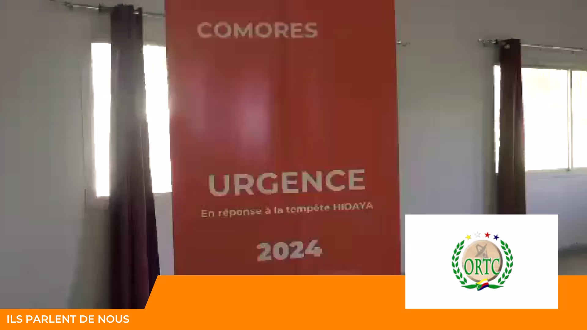 Bannière orange « Comores – Urgence en réponse à la tempête Hidaya 2024 » dans une salle, logo ORTC en incrustation