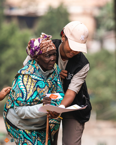 Sandrine, coordinatrice pays de l'ONG LIFE aidant une personne âgée lors d'une distribution alimentaire