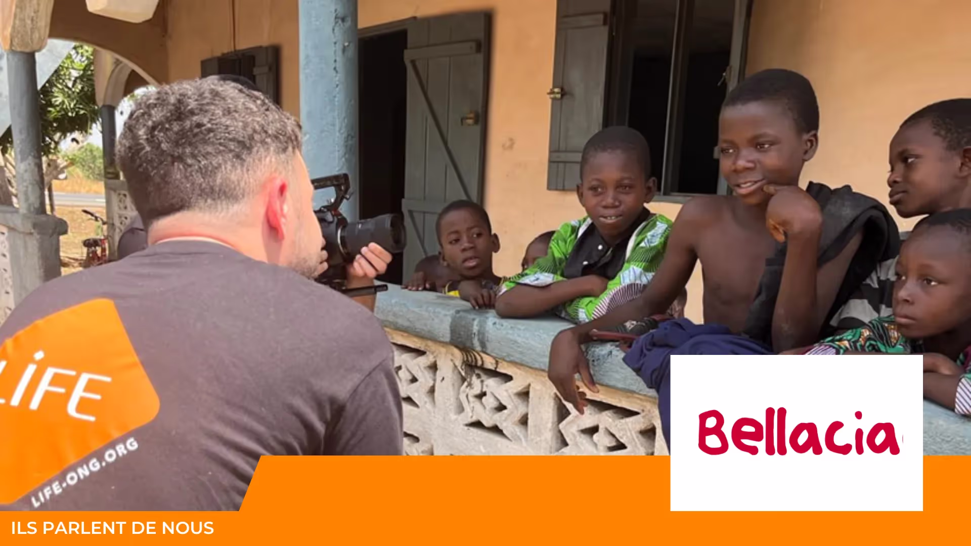 Un homme en t-shirt LIFE filme avec une caméra des enfants accoudés à un muret ; logo Bellacia et mention « Ils parlent de nous »
