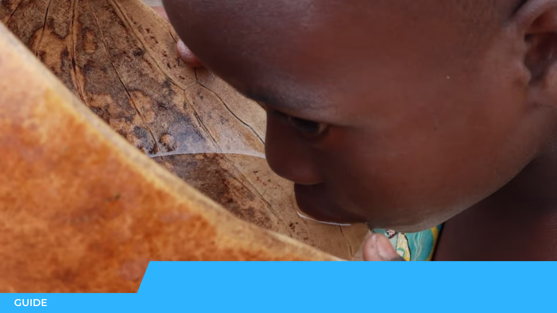 Gros plan sur le visage d'un enfant penché au-dessus d'un grand récipient végétal brun, avec le bandeau « Guide »