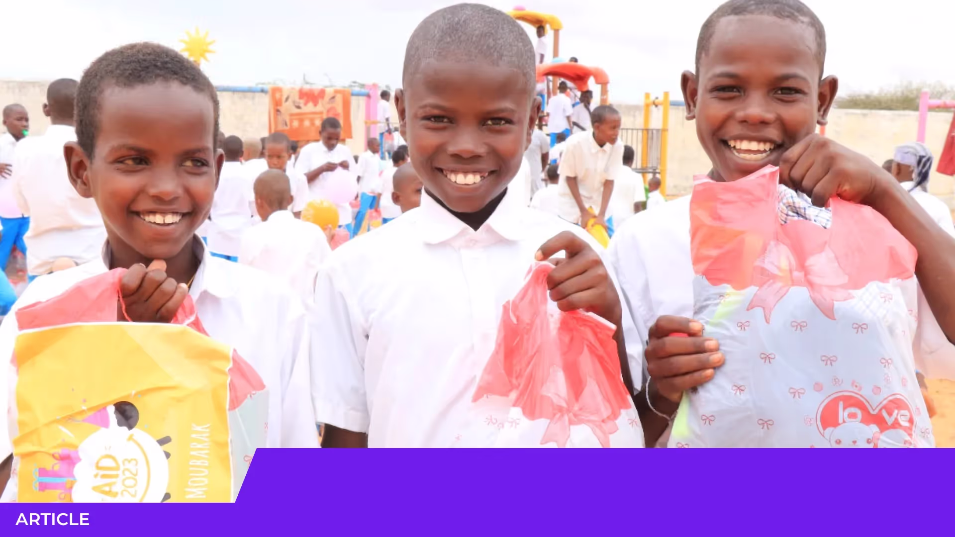 Trois garçons en chemise blanche souriant et montrant des sachets cadeaux de l'Aïd 2023 dans une cour d'école