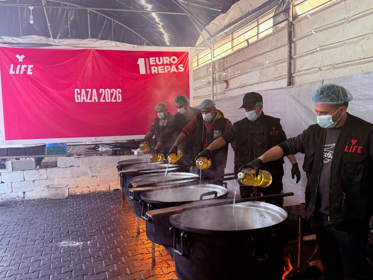 Des bénévoles LIFE versent de l'huile dans de grandes marmites devant une banderole « 1 euro repas, Gaza 2026 »