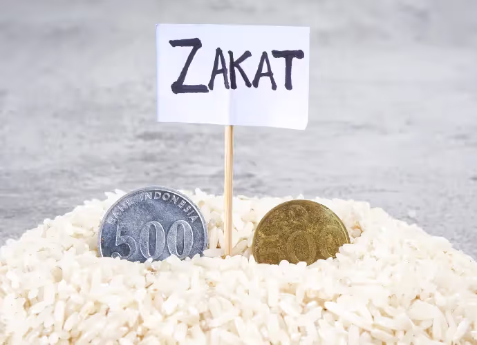 Pile de riz avec deux pièces de monnaie indonésiennes et un petit drapeau en papier portant le mot « ZAKAT »