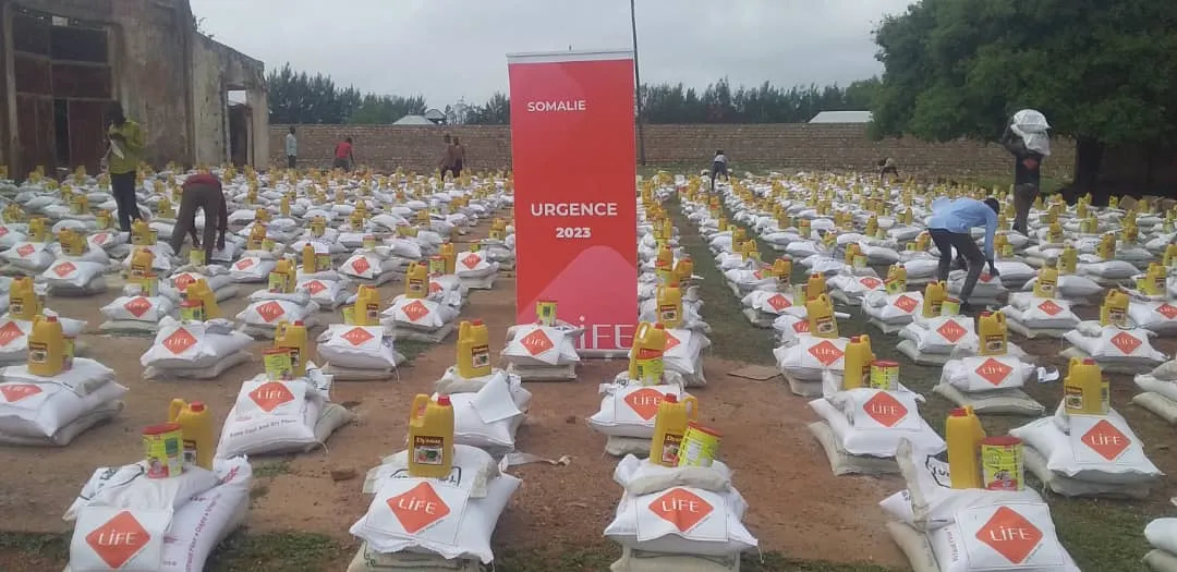 Distribution LIFE en Somalie en 2023 : rangées de sacs de riz et de bidons d'huile alignés dans une cour, avec des bénévoles