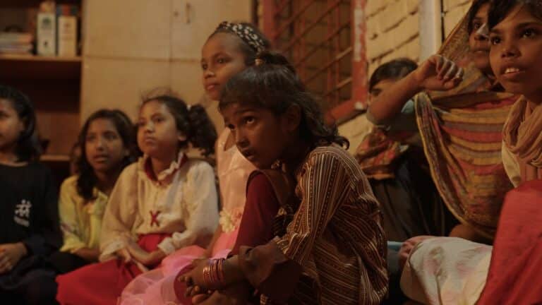 Groupe de fillettes assises côte à côte dans une pièce, regardant attentivement dans la même direction lors d'une activité