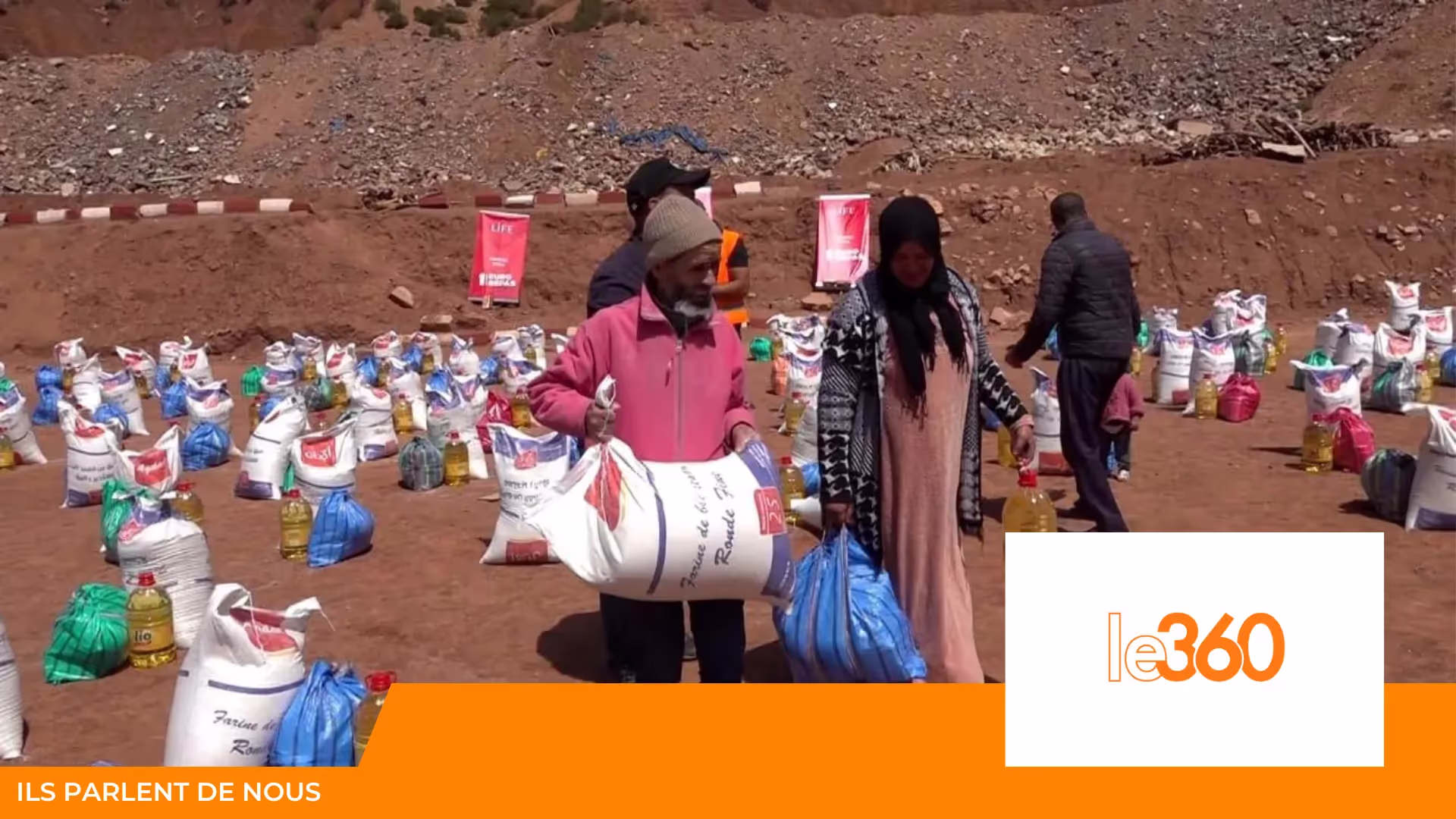 Distribution de sacs de farine, bouteilles d'huile et colis à des villageois, bannières LIFE ; logo le360 en bas à droite